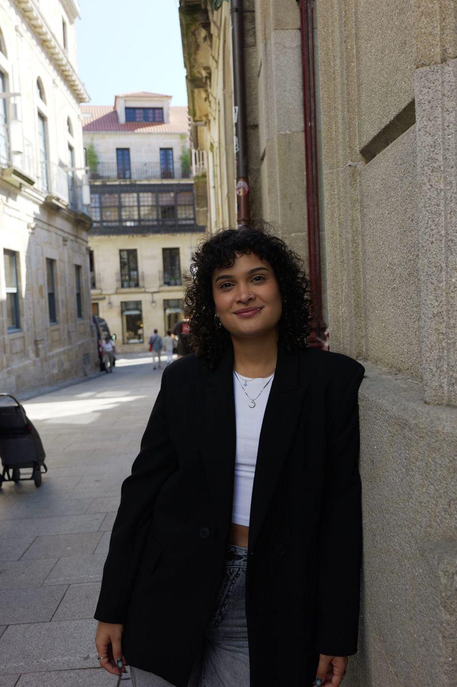 Verónica con blazer negro apoyada en una fachada de piedra