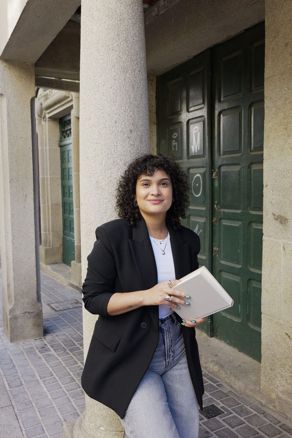 Verónica con un cuaderno en la mano, apoyada en una columna de granito