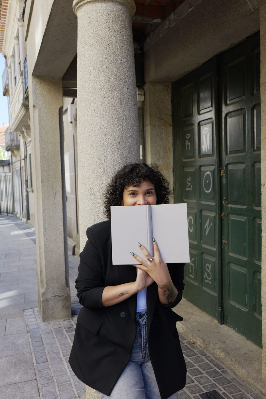 Verónica tapándose la cara con un libro abierto, sonriendo